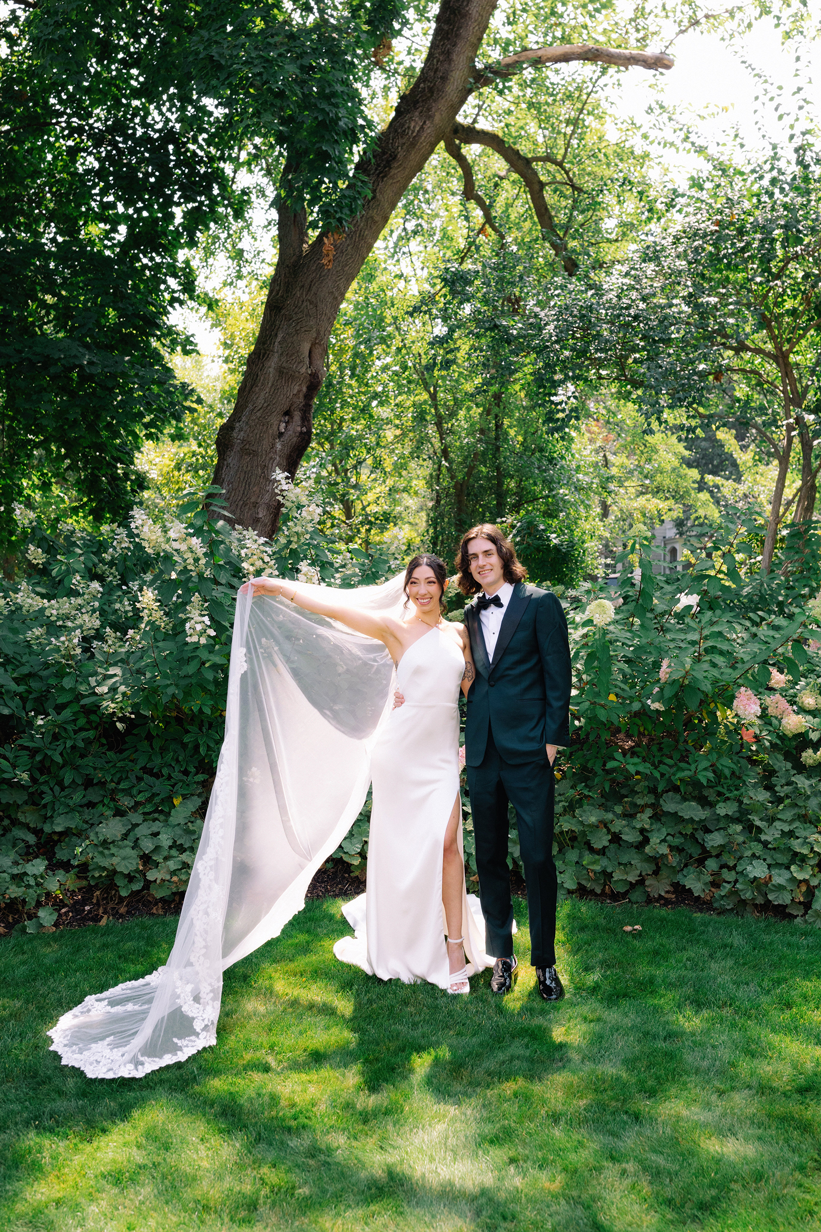Bride and groom with effortless elegant pose backlit in a lush garden in a Chicago backyard before they are married